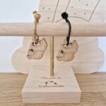 Deux porte-clés en bois ours de la marque Les Petites Hirondelles avec un lien vert et un lien doré sur un présentoir en bois