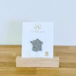 Pin's feutrine pailletée argent en forme de carte de la France